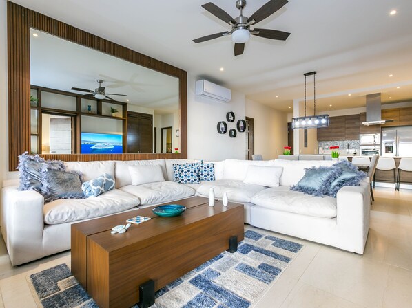 Relax in the spacious living room featuring a large sectional perfect for lounging and socializing. The open-concept design is ideal for watching TV, enjoying a good book, or simply unwinding after a day of exploring. Natural light fills the room, creating a warm and inviting atmosphere.