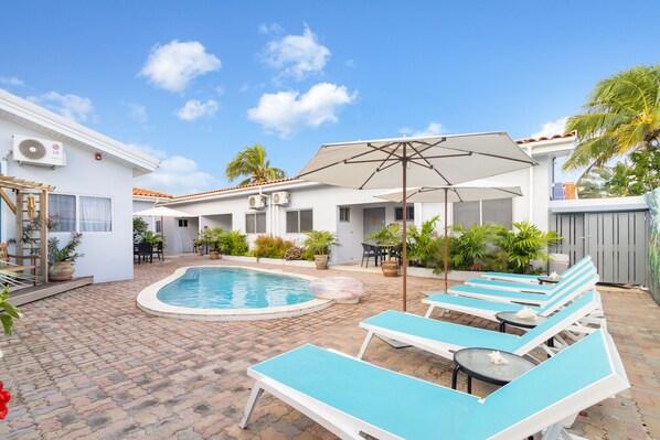 Amazing pool area of the villa in Noord, Aruba - Cosy beach chairs and neat and clean towels available - Beautiful mountain view - Superbly designed pool area - Refreshing Environment - Vibrant Atmosphere - Great sitting under umbrella shades