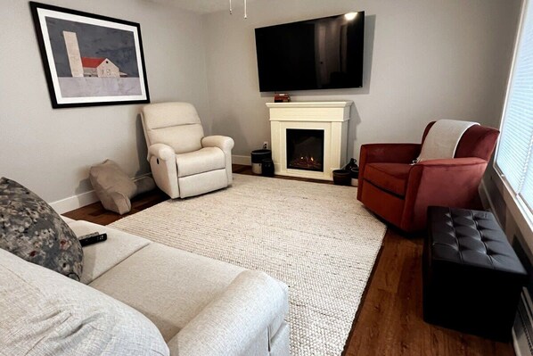 Living room with fireplace and smart TV for your favorite streaming and unique Amish Country watercolor. 