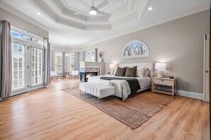 Spacious primary bedroom featuring a 75 inch tv, fireplace, and sunroom.