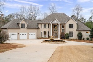 Front view featuring massive driveway, 3-car garage, and fountain.