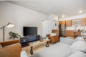 Cozy minimal living room with elegant wooden furniture. Plush couch, sleek TV, and warm tones offer relaxation and entertainment.