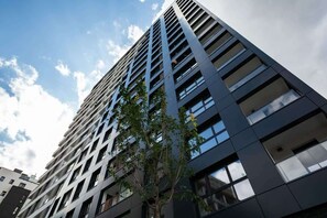 An exterior shot of the apartment building, showcasing its contemporary high-rise design with black and glass finishes.

