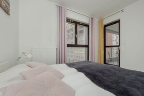 Another perspective of the bedroom, highlighting a neatly made bed, soft pillows, and large windows providing a great city view.

