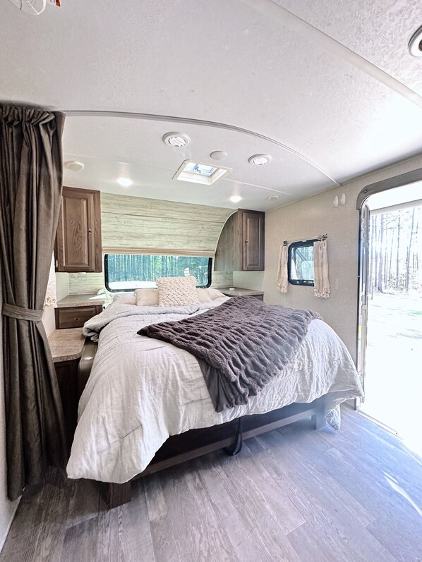 RV bedroom: bed, window. Cozy travel space.