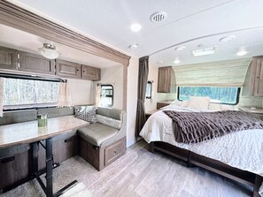 RV interior: booth seating, bed. Compact living space.