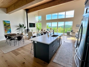 Lovely, modern kitchen, dining, and living space on the main level with large windows and mountain views.