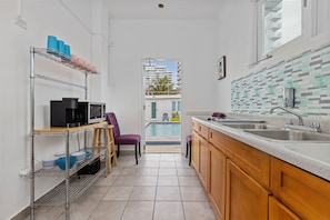 Fully stocked kitchen with a view of the pool. Stainless steel appliances, including a refrigerator and oven, along with ample counter space and modern cabinets. Large window brings in natural light and highlights the pool area.
