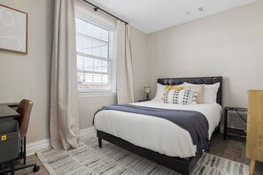This bedroom features a cozy bed and workspace.