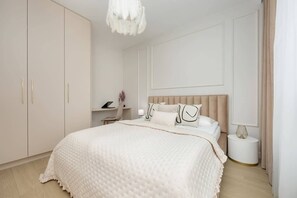 A serene bedroom with a large bed, floor-to-ceiling curtains, and built-in wardrobes, offering a peaceful and comfortable retreat.

