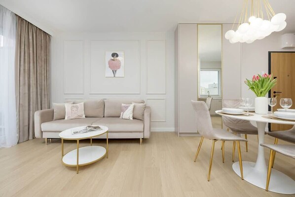 A bright and elegant living room with a soft beige color scheme, a round coffee table, plush seating, and a stylish wall portrait, creating a luxurious and cozy atmosphere.

