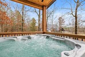 A hot tub under a covered patio offers a private and soothing retreat with a view of the serene natural surroundings.