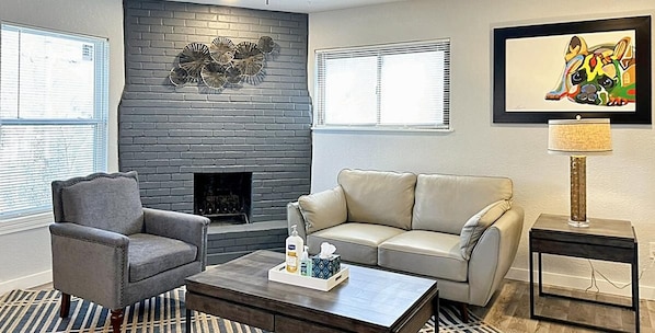 Sunlight-filled living area with comfy gray couch & armchair invites relaxation with a touch of modern style.