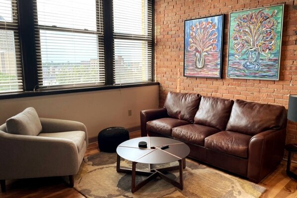 Living room with views and leather sofa, exposed brick wall