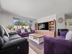  A spacious open-plan living area with plush seating, a cosy fireplace, and a large TV for movie nights.