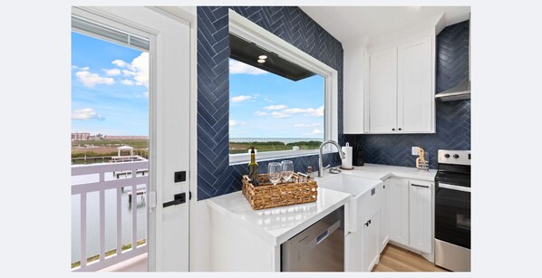 Unit 201 Kitchen:
Take in the serene views just outside the window as you prepare meals in the chef-inspired kitchen. Enjoy a warm cup of coffee or tea at the quartz-topped island, fully stocked with all the essentials. This sleek and modern space features stainless steel appliances, a stylish tile backsplash, custom cabinetry with built-in trash bins, and a convenient spice ra...