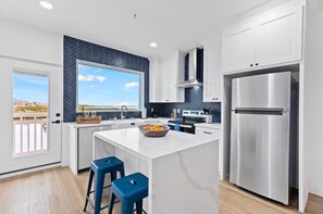 Unit 201 Kitchen:
Take in the serene views just outside the window as you prepare meals in the chef-inspired kitchen. Enjoy a warm cup of coffee or tea at the quartz-topped island, fully stocked with all the essentials. This sleek and modern space features stainless steel appliances, a stylish tile backsplash, custom cabinetry with built-in trash bins, and a convenient spice ra...