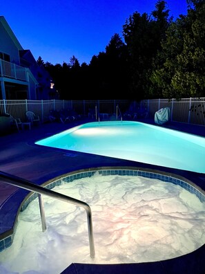 Lighted view of seasonal in-ground pool and hot tub