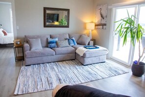 This inviting living room offers a gray couch, plush carpet, and a sliding door giving you full access to the wrap around balcony. This space offers the perfect ambiance for relaxation.