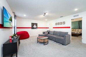 Relax in this Mickey Mouse-themed room with a cozy sectional, vibrant decor, and a large TV for endless entertainment.
