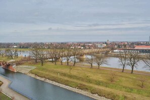 A scenic view of a riverbank with lush greenery and a calm waterway, showcasing the beautiful surroundings near the apartment.