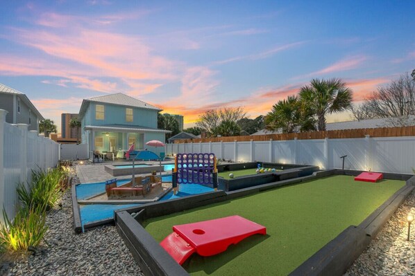 Inviting backyard oasis complete with corn hole, a kids' play zone, and a life-sized kick pool, ensuring endless fun and entertainment for all ages