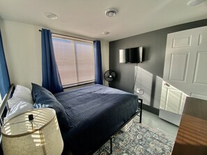 Queen bedroom with tv, fan, hangers, and dresser