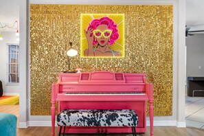 As your gaze sweeps across this enchanting tableau, the pink piano stands as the focal point, its rosy hue exuding charm and vitality. Against the backdrop of the gleaming gold wall, every keystroke becomes a symphony of elegance and grace.