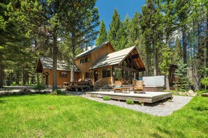 Surrounded by lush greenery, this charming cabin features a spacious deck, inviting seating areas, and a private hot tub, offering the perfect escape into nature.