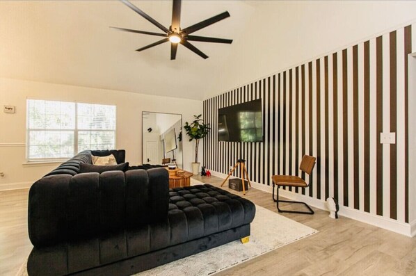 Spacious and stylish living room featuring modern decor, a cozy sectional, and plenty of natural light — perfect for relaxing after a day of exploring Savannah.