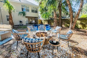 Gather around this inviting outdoor fire pit area, complete with comfortable seating and lush greenery for the perfect evening under the stars.