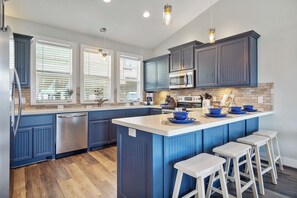 One Love Kitchen: Unwind with a glass of wine and culinary creativity in our coastal vacation home, featuring a chef's kitchen with a peninsula island.