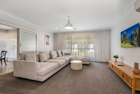 Lounge room with flat screen TV and large couch.
