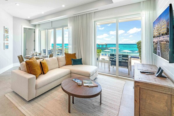 Oceanfront living area with HD television, sectional sofa, and walk-out access to the beach. 
