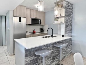 Beautifully redesigned kitchen. Quartz tops, sleek stovetop, microwave, fridge