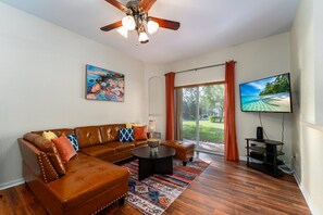 Living room showing sofa, TV, and patio access