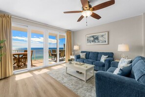 Relax in the cozy living room featuring a sleeper sofa, smart TV, and floor-to-ceiling windows that open to a stunning oceanfront balcony