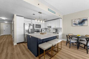Modern kitchen and dining area with a large island, stainless steel appliances, and comfortable seating, perfect for gathering and meals