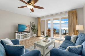 Relax in the cozy living room featuring a sleeper sofa, smart TV, and floor-to-ceiling windows that open to a stunning oceanfront balcony