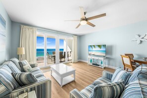 Unwind in a bright and airy living room featuring a queen-size sleeper sofa, a smart TV, and stunning ocean views through floor-to-ceiling windows leading to a private balcony