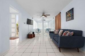 The living room offers a comfortable sofa, flat screen TV and a seating area with tons of natural light.