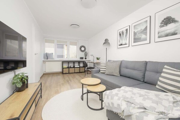 A bright living room with a large gray sofa, a round coffee table, and framed artwork on the walls, creating a stylish and cozy atmosphere.

