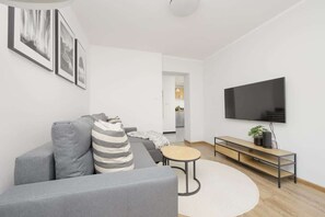 A second view of the living space, showcasing a mounted TV, a stylish gray couch, and decorative pillows enhancing the design.

