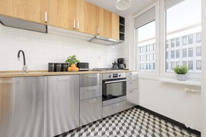 A sleek kitchen with wooden cabinets, stainless steel appliances, and a large window allowing natural light to brighten the space.

