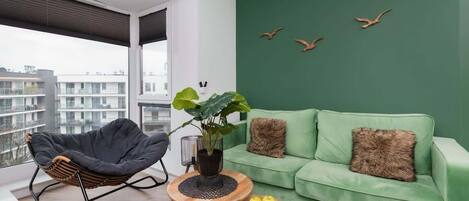 A stylish living room with a deep green accent wall, a matching green sofa, and a cozy round coffee table, creating a modern and inviting space.