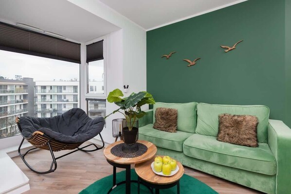 A stylish living room with a deep green accent wall, a matching green sofa, and a cozy round coffee table, creating a modern and inviting space.

