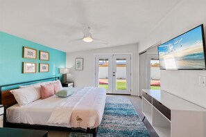 Primary bedroom with king size bed, TV & doors leading to the backyard.