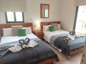 This bedroom has two double beds, a balcony overlooking the pool and built in wardrobes & Aircon