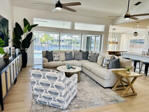 Gorgeous designer living room with 75” TV and panoramic views of pool and water