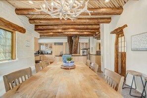 Gather around the charming wooden dining table, where natural light floods in and the live tree adds a touch of greenery to the kitchen backdrop.